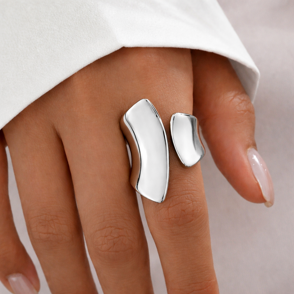 Silver ring on a finger with a plain background