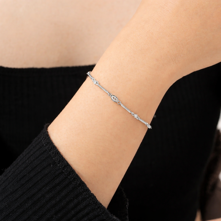 Silver bracelet on a person's wrist with a plain background