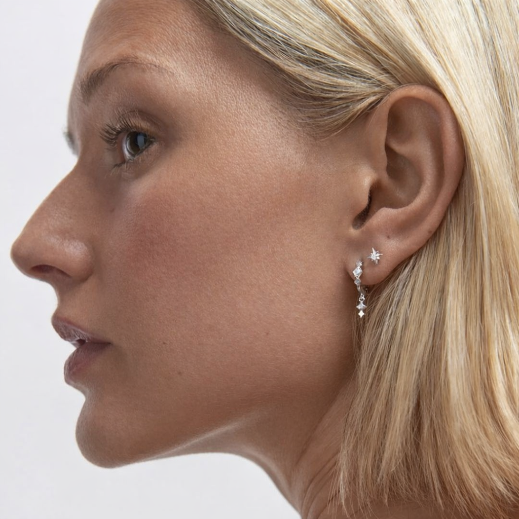 Close-up of a woman wearing star-shaped earrings on a plain background