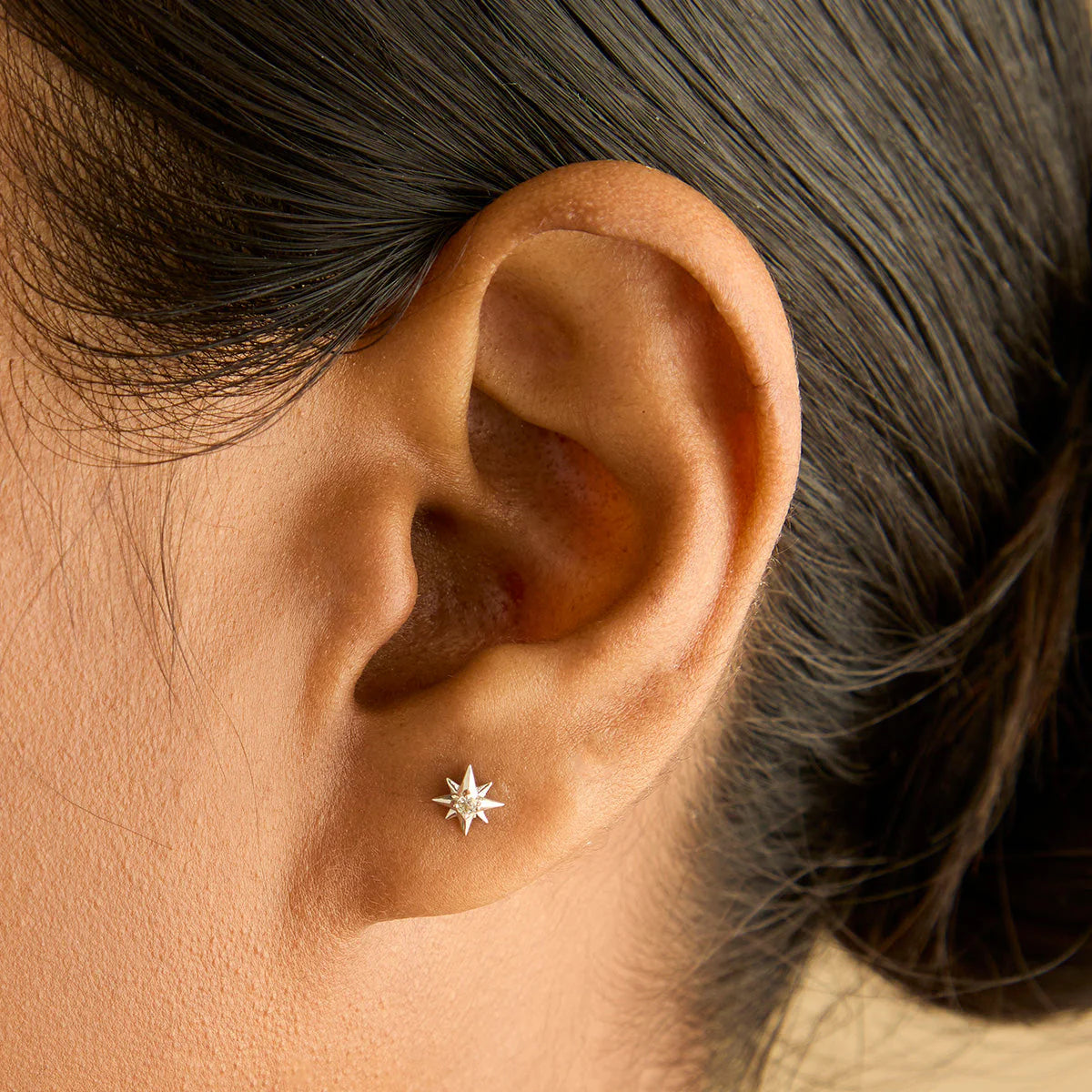 Close-up of an ear wearing a star-shaped silver earring.
