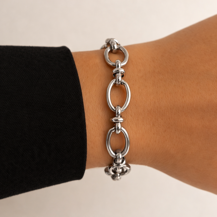 Silver chain bracelet on a wrist with a neutral background