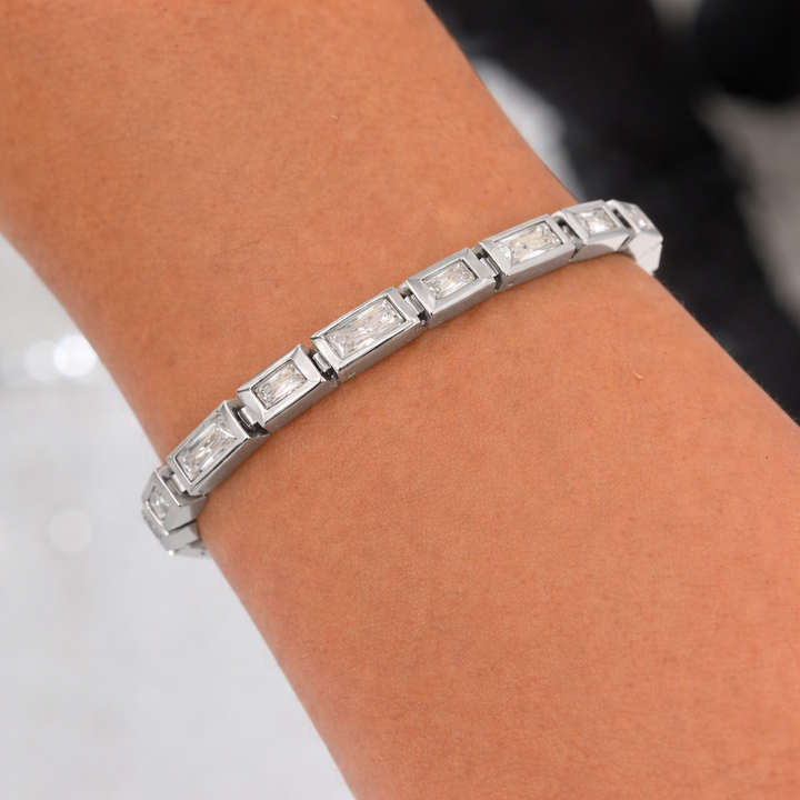 Silver bracelet with square-cut gemstones on a wrist against a neutral background