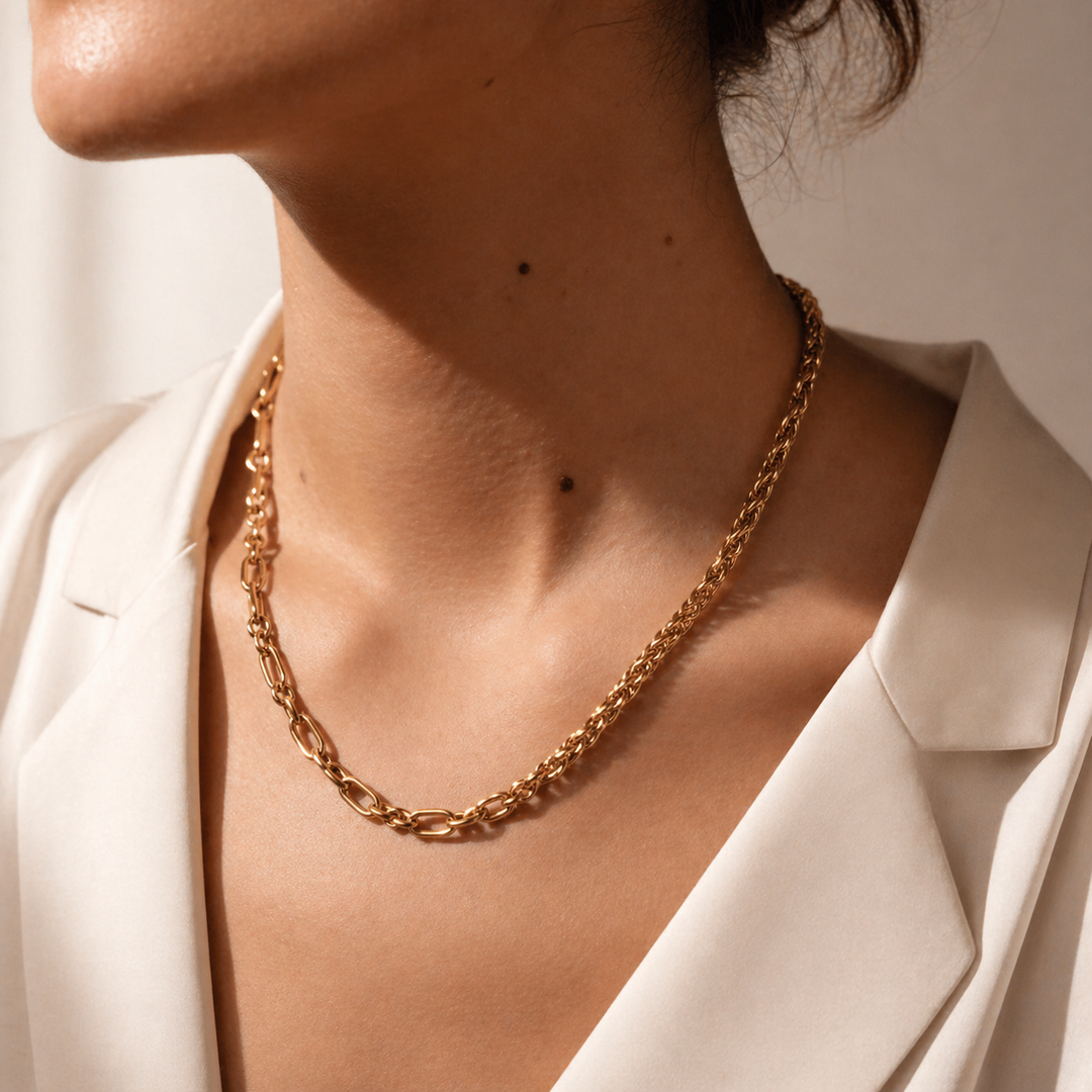 Gold chain necklace worn by a person in a white blazer.
