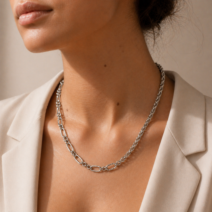 Silver chain necklace worn by a person with a neutral background