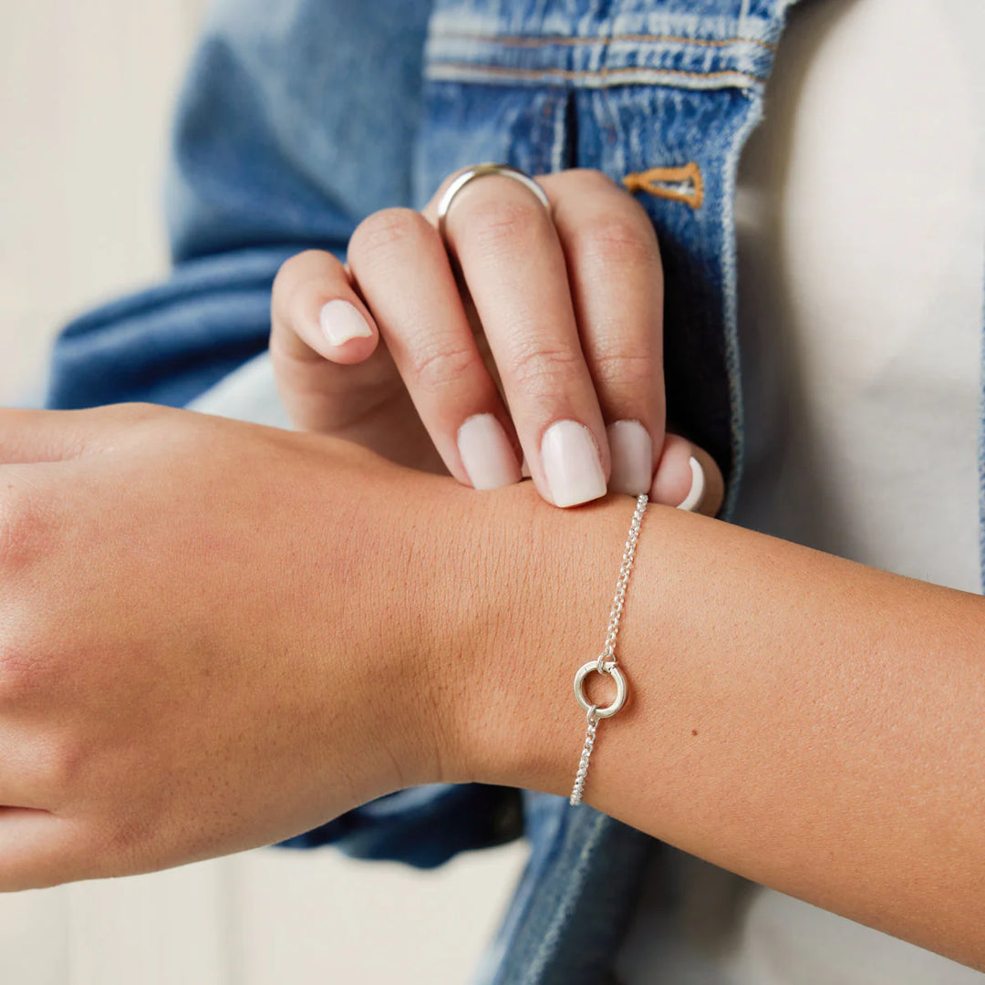 Close-up of a person wearing a silver bracelet on their wrist.