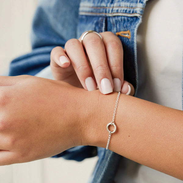 Close-up of a person wearing a silver bracelet on their wrist.