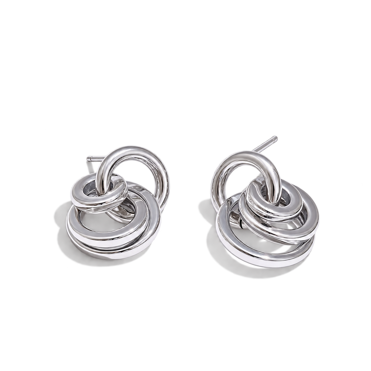 A pair of polished silver-toned drop earrings with interlocking concentric rings, shown on a clean white background.