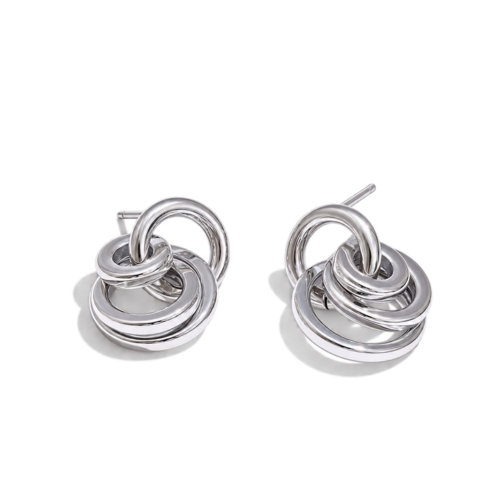 A pair of polished silver-toned drop earrings with interlocking concentric rings, shown on a clean white background.