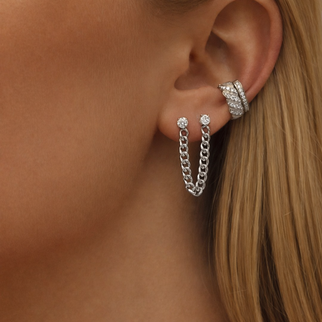 Close-up of an ear wearing silver earrings with a blurred background