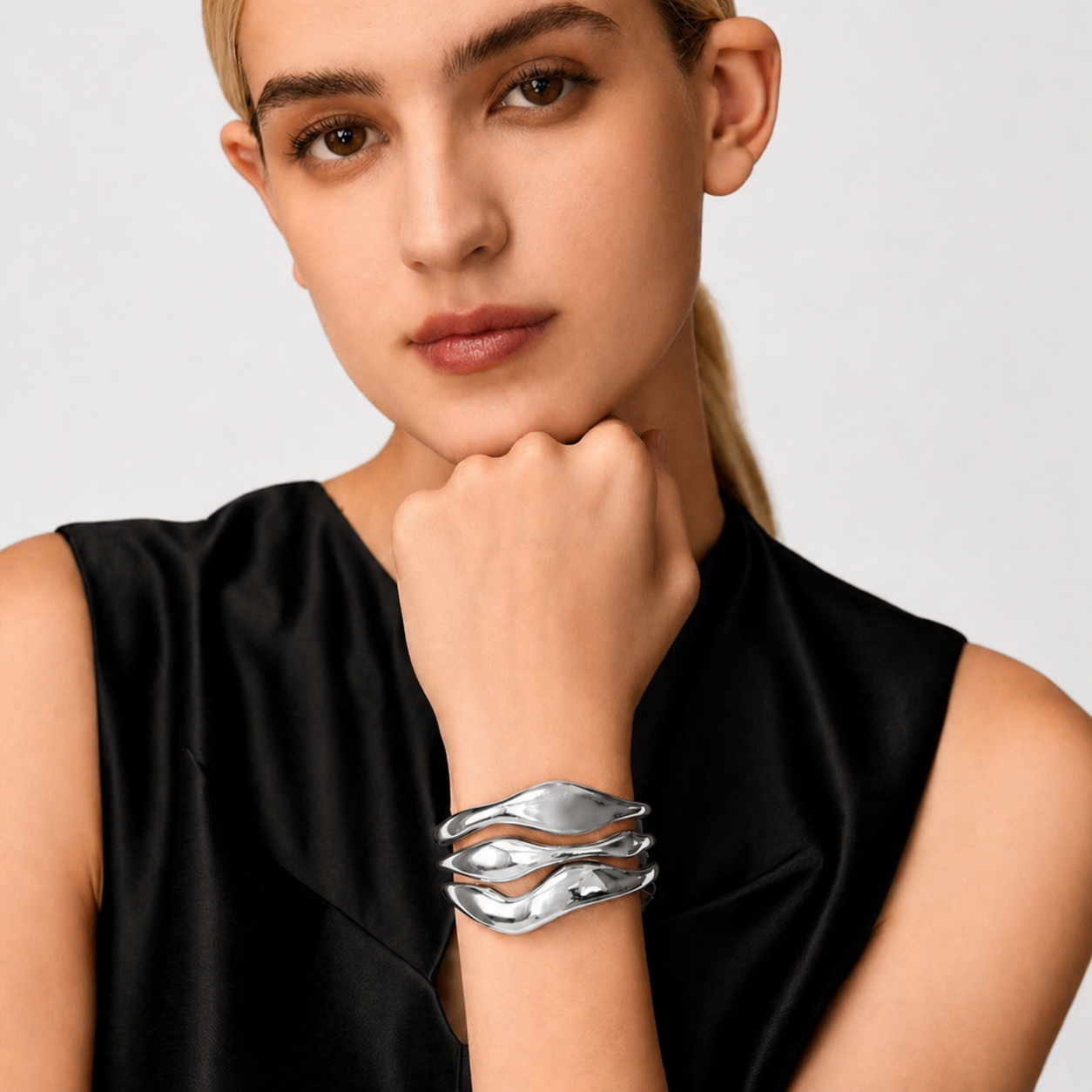 Woman wearing a silver bracelet on a plain background