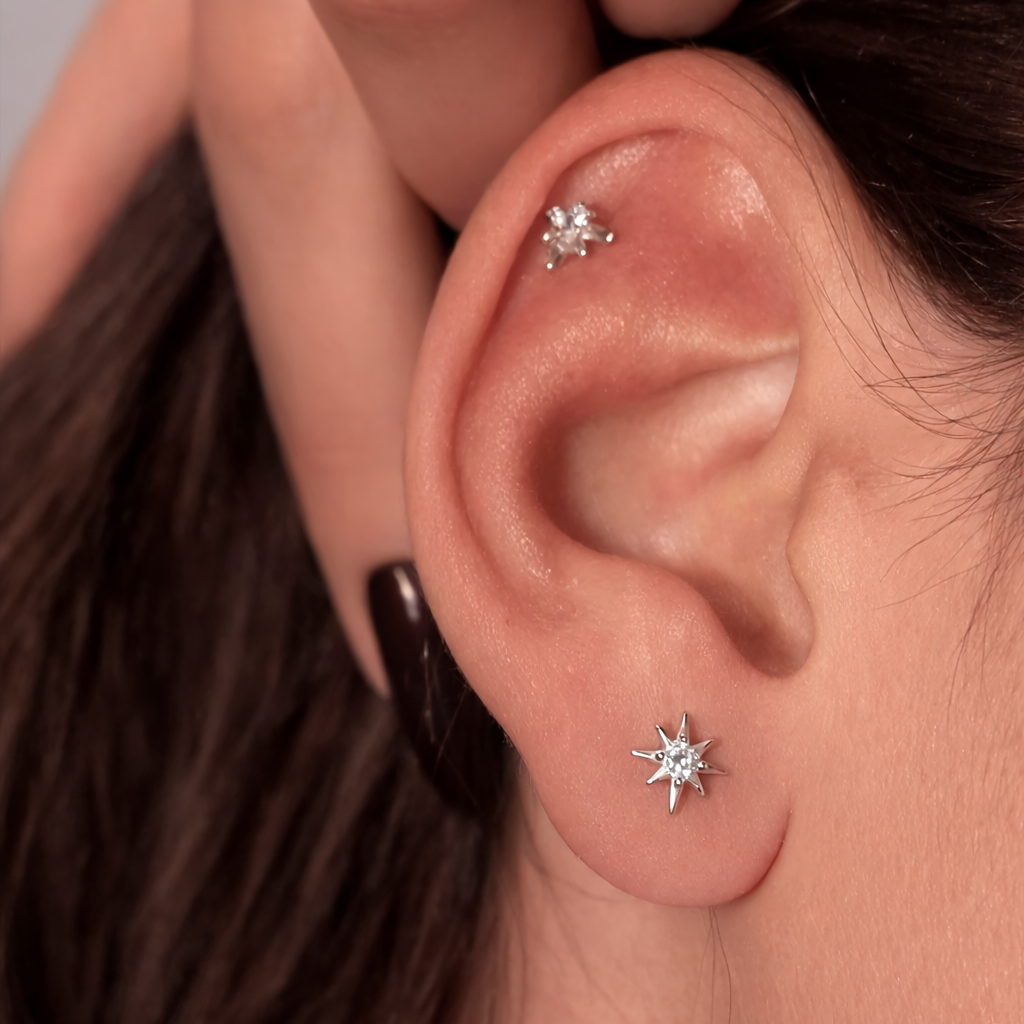 Close-up of a person wearing two diamond stud earrings.