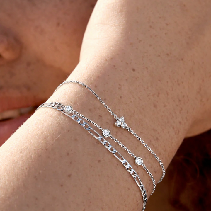 Close-up of a person's wrist wearing multiple silver bracelets.