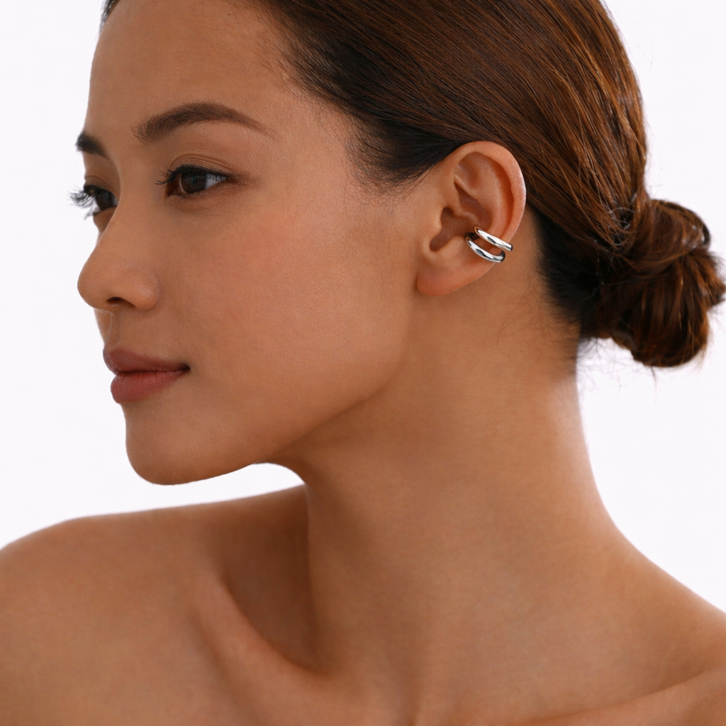 Close-up of a woman wearing a silver hoop ear cuff earring on a white background