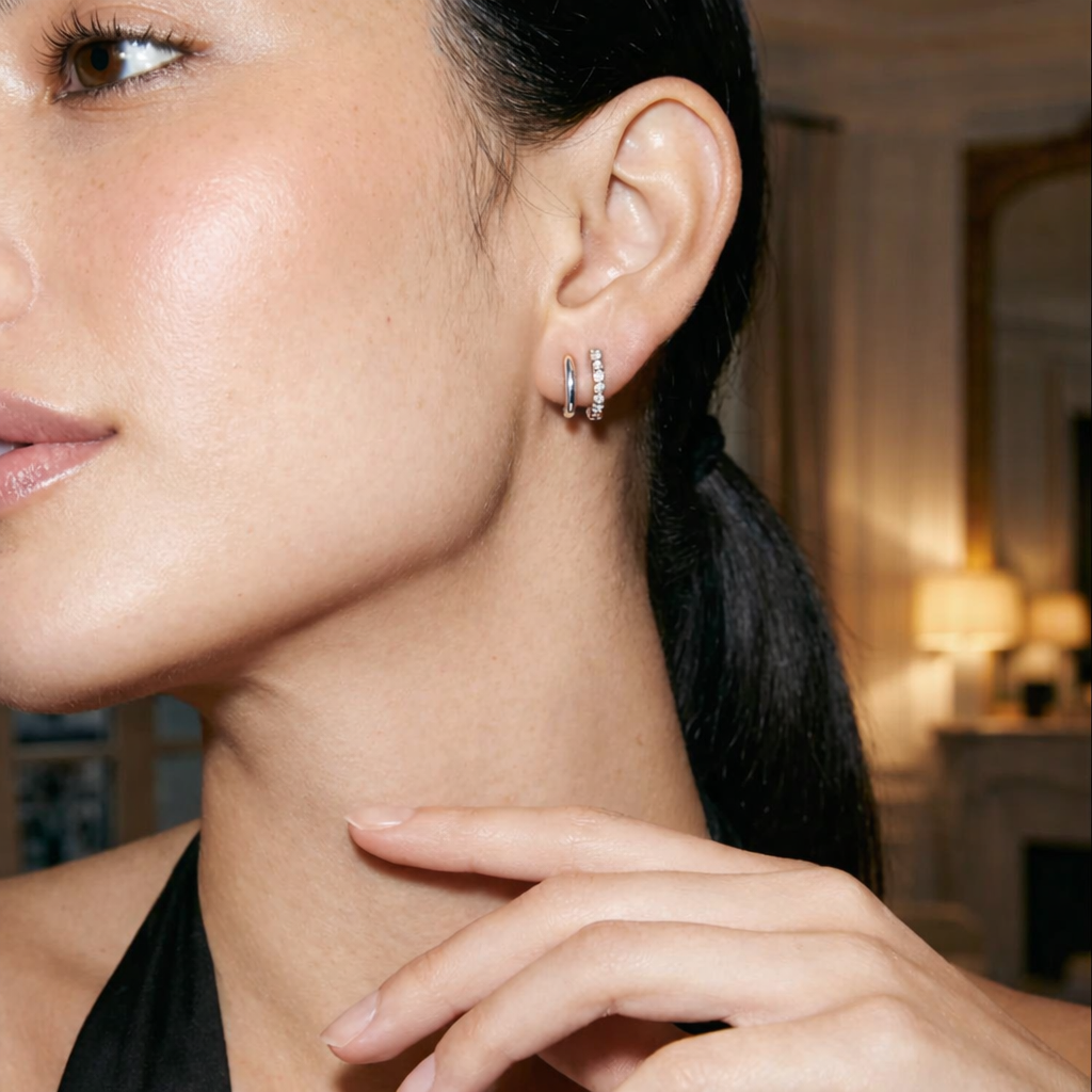 Close-up of a woman wearing pearl hoop earrings with a blurred indoor background