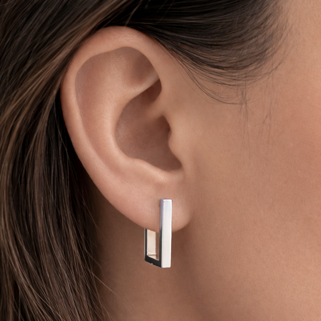 Close-up of an ear wearing a silver hoop earring with a blurred background