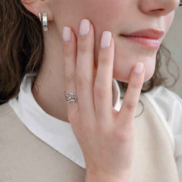 Close-up of a person wearing two silver rings on their fingers.