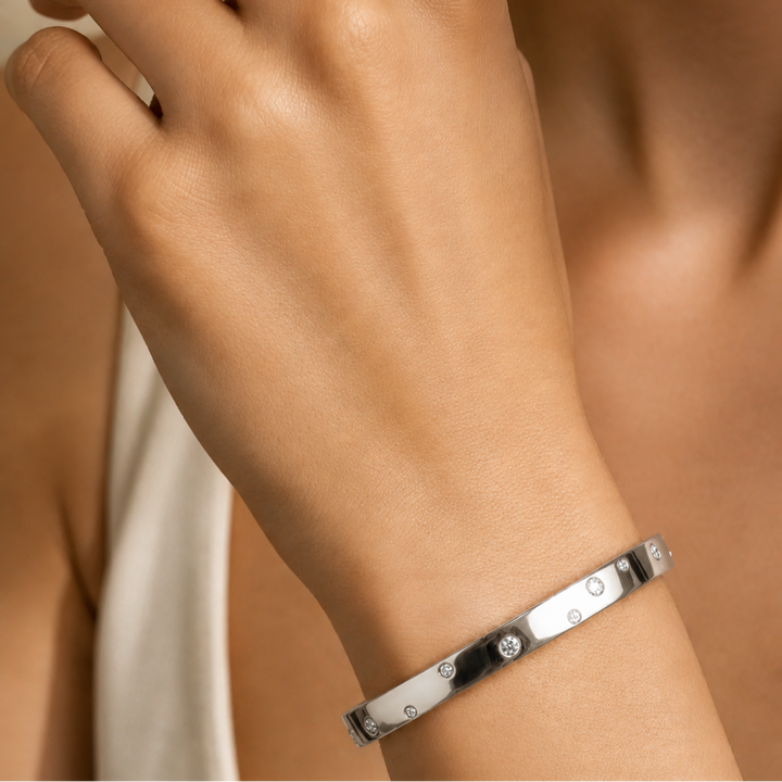 Close-up of a hand wearing a silver bracelet on a neutral background