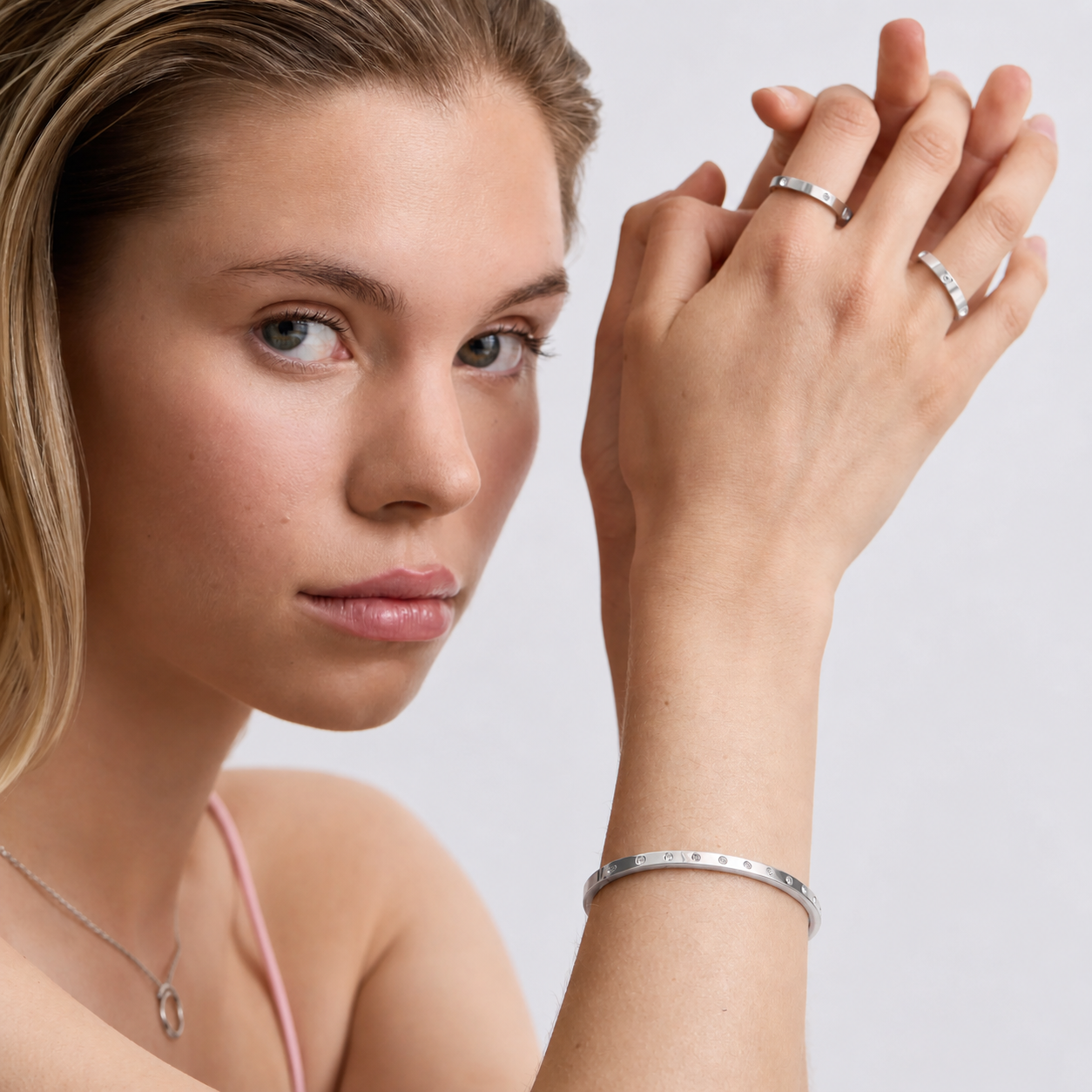 Woman wearing silver jewelry including a ring and bracelet on a plain background