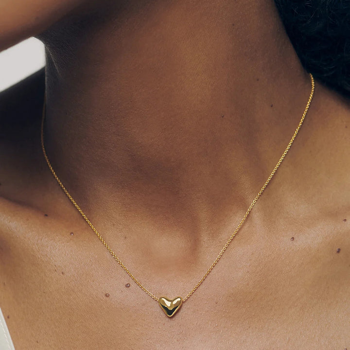 Gold heart necklace on a person's neck