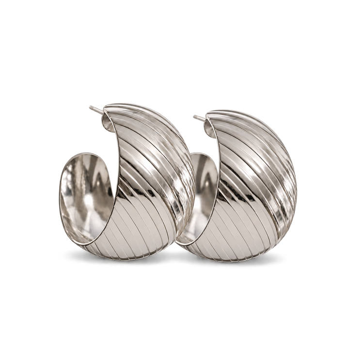 A pair of large, polished silver hoop earrings with a distinctive ribbed, fluted texture, displayed on a clean white background.