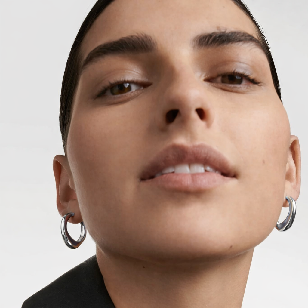 Close-up of a person wearing light weight hoop earrings with a neutral background