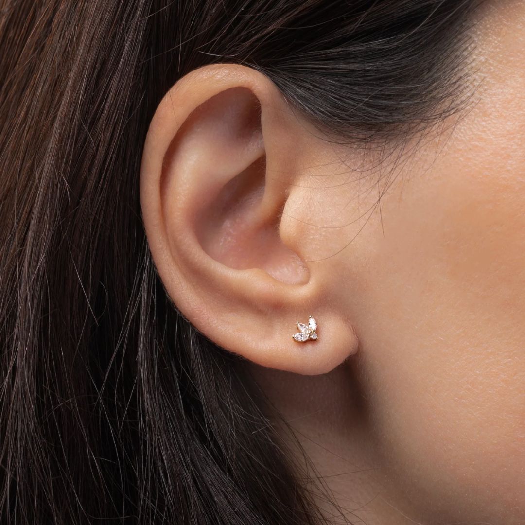 Close-up of an ear wearing a small silver earring with a butterfly design.
