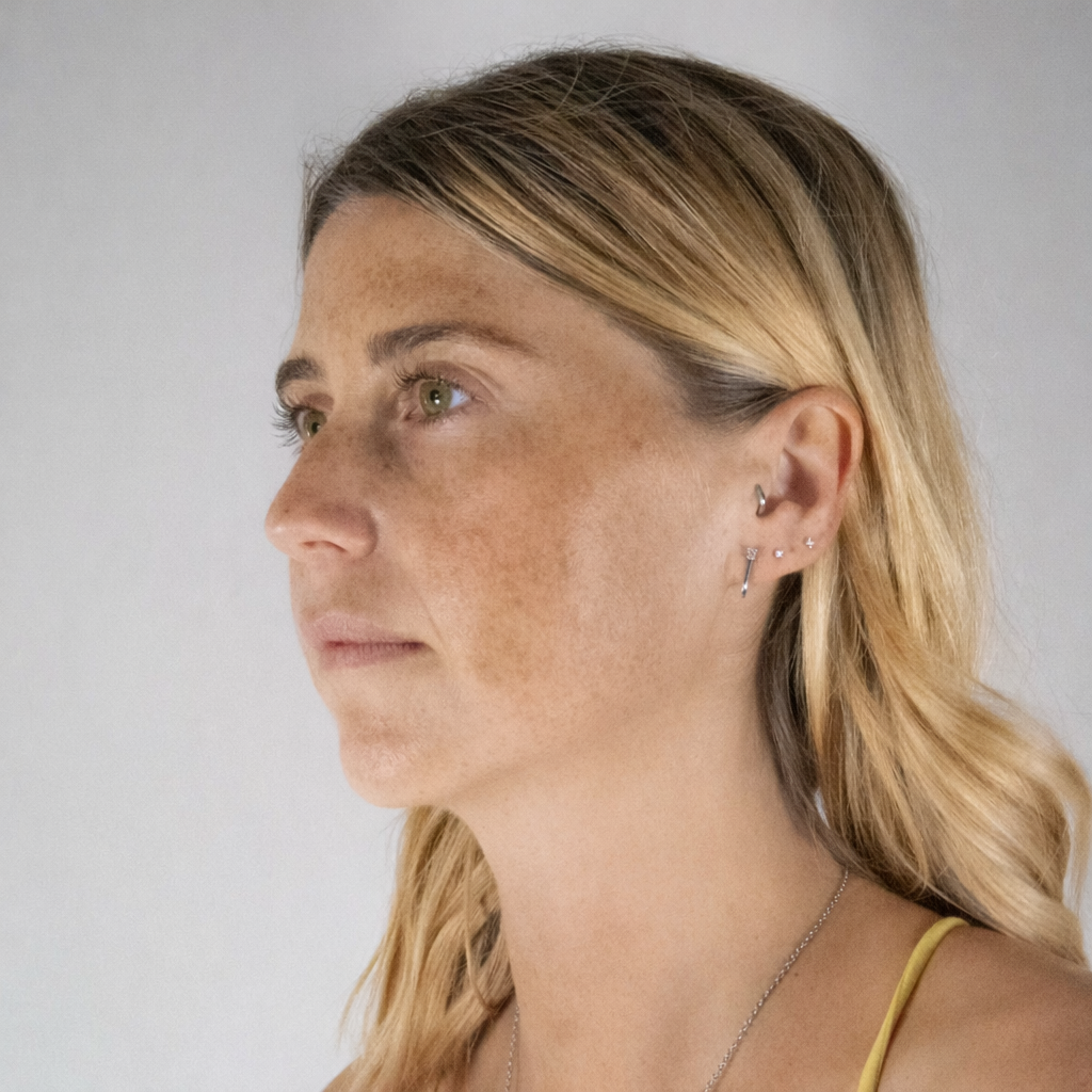 Side profile of a woman with blonde hair and freckles on a plain background