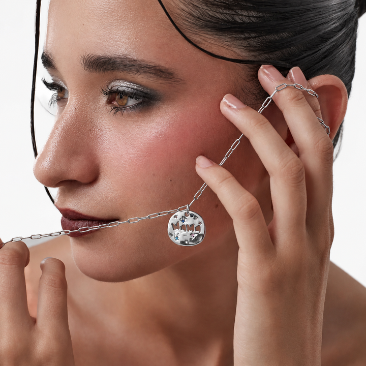 Woman wearing a silver earring with a visible brand name.