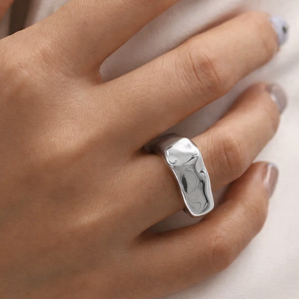 Silver ring on a person's finger with a neutral background