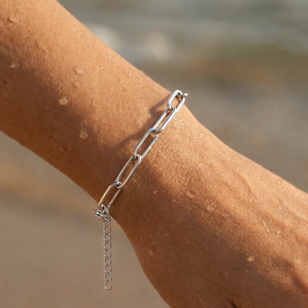 Silver chain bracelet on a person's wrist with a blurred beach background