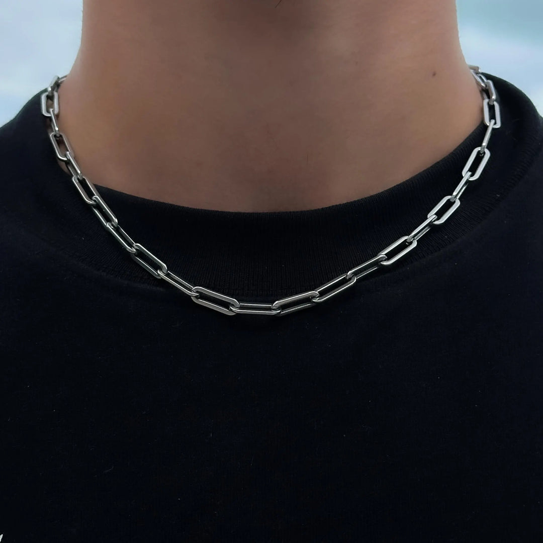Silver chain necklace worn by a person on a black background