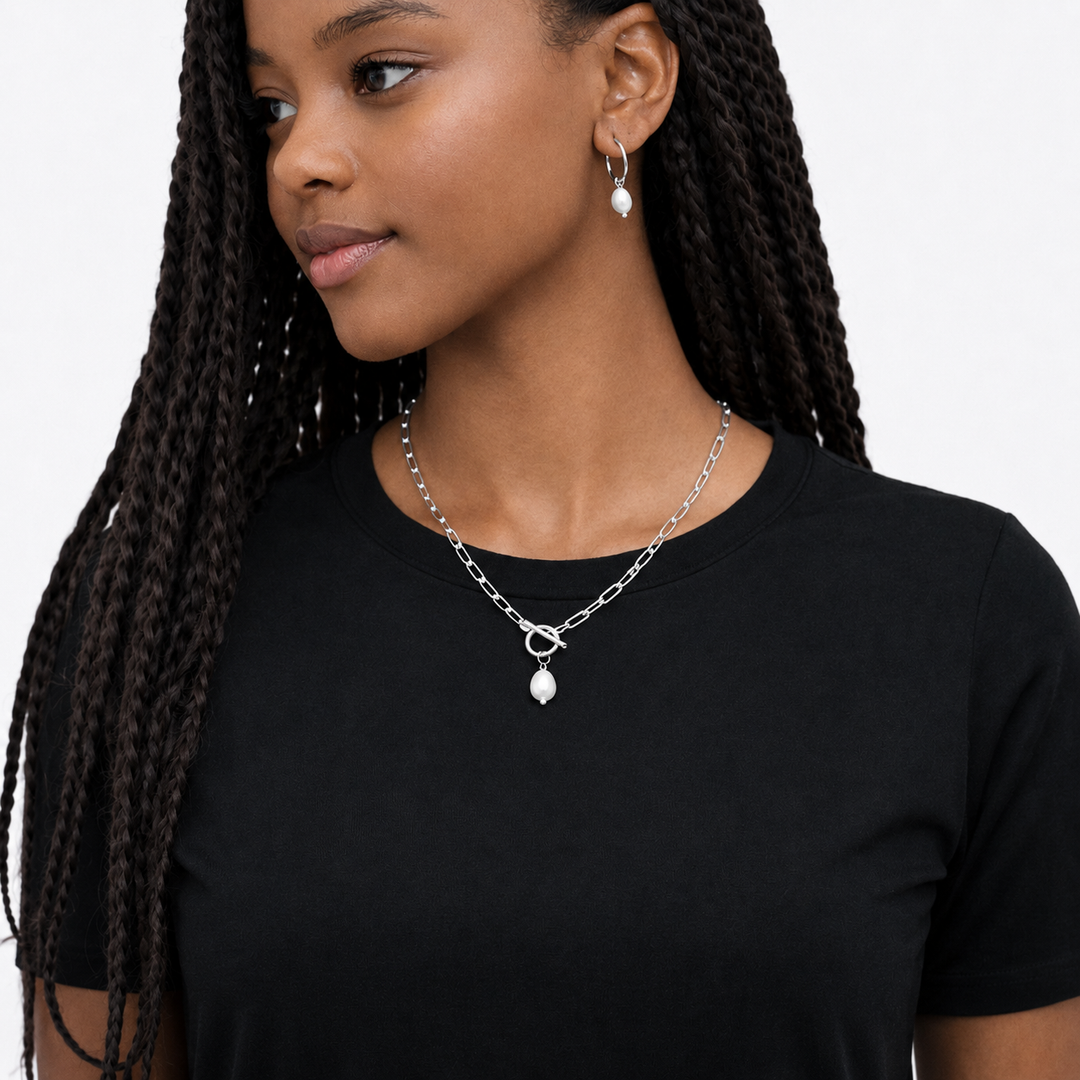 Woman wearing a silver necklace with pendant on a plain background