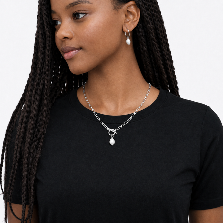 Woman wearing a silver necklace with pendant on a plain background
