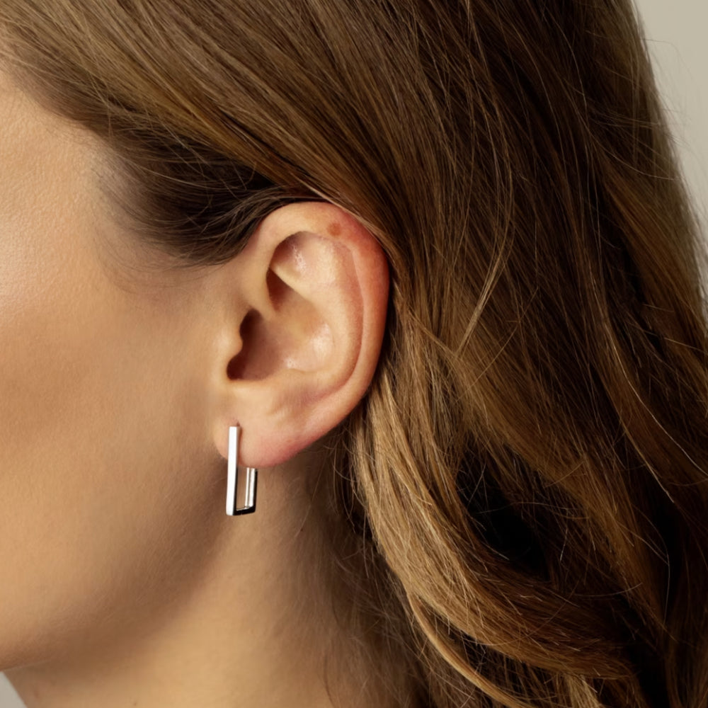 Silver hoop earring worn by a person with brown hair.