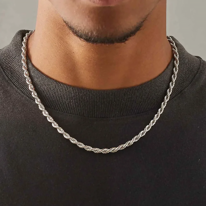 Silver rope chain necklace worn by a person on a plain background