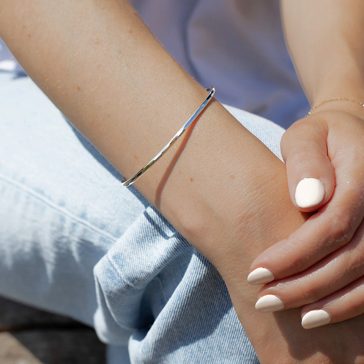 Silver bracelet on a wrist with a blurred background