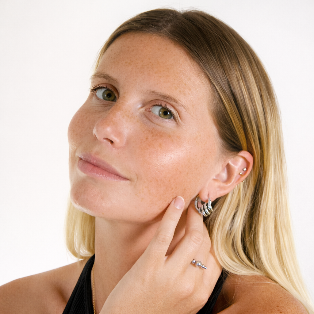 Woman adjusting an earring against a white background