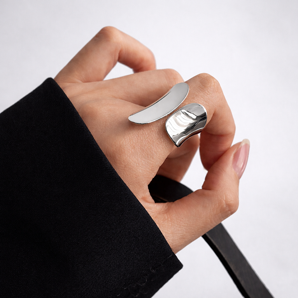 Hand wearing a silver ring on a light gray background