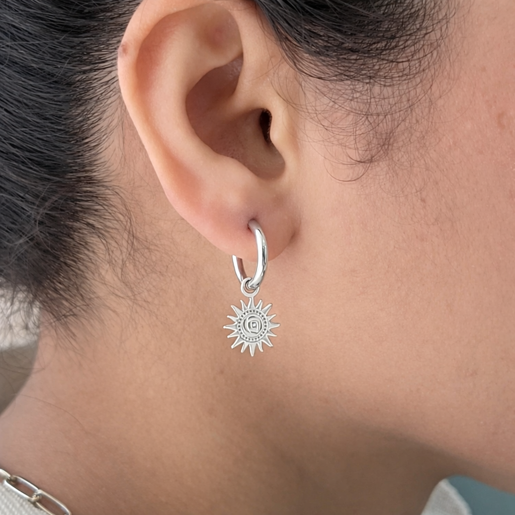 Silver hoop earring with a star-shaped charm worn by a person.