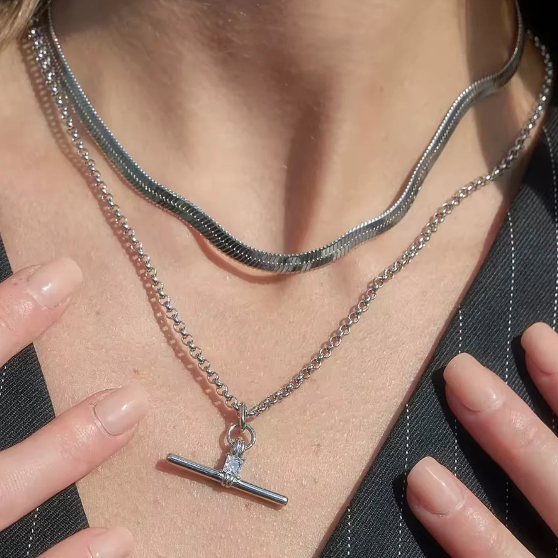 Close-up of a person wearing a silver necklace with a pendant.