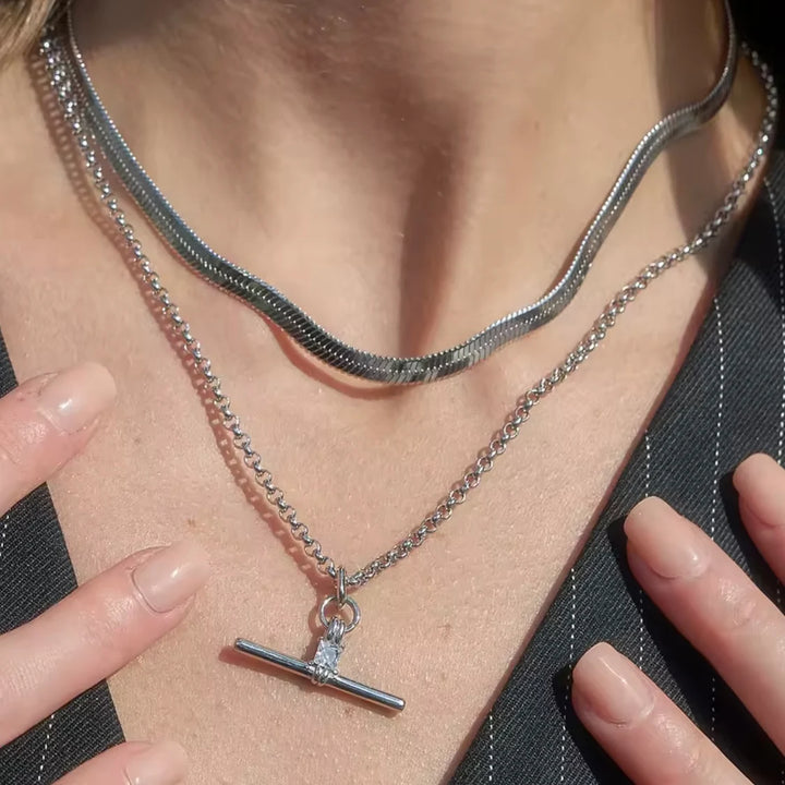 Close-up of a person wearing a silver necklace with a pendant.