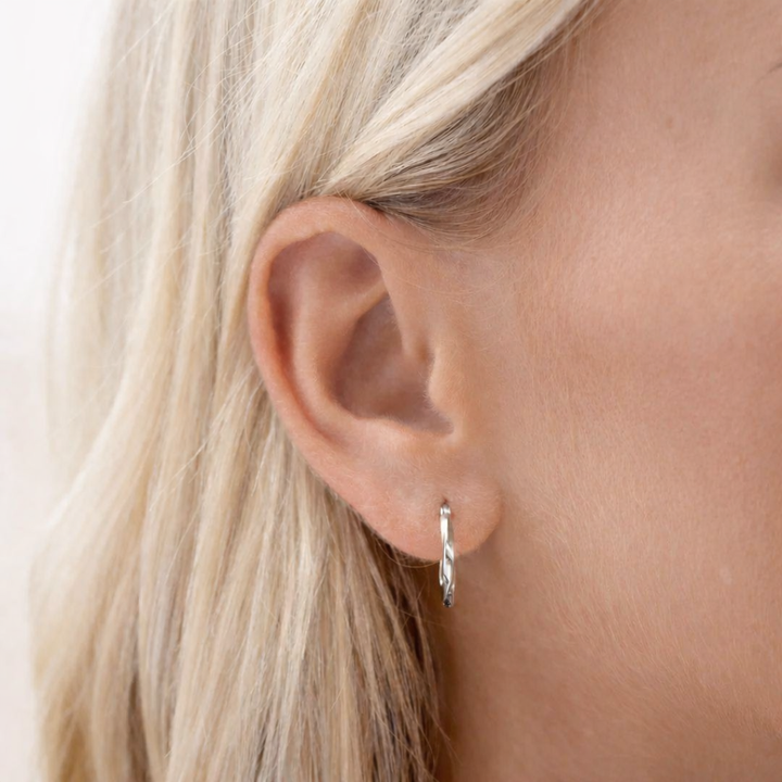 Silver hoop earring worn by a person with blonde hair.