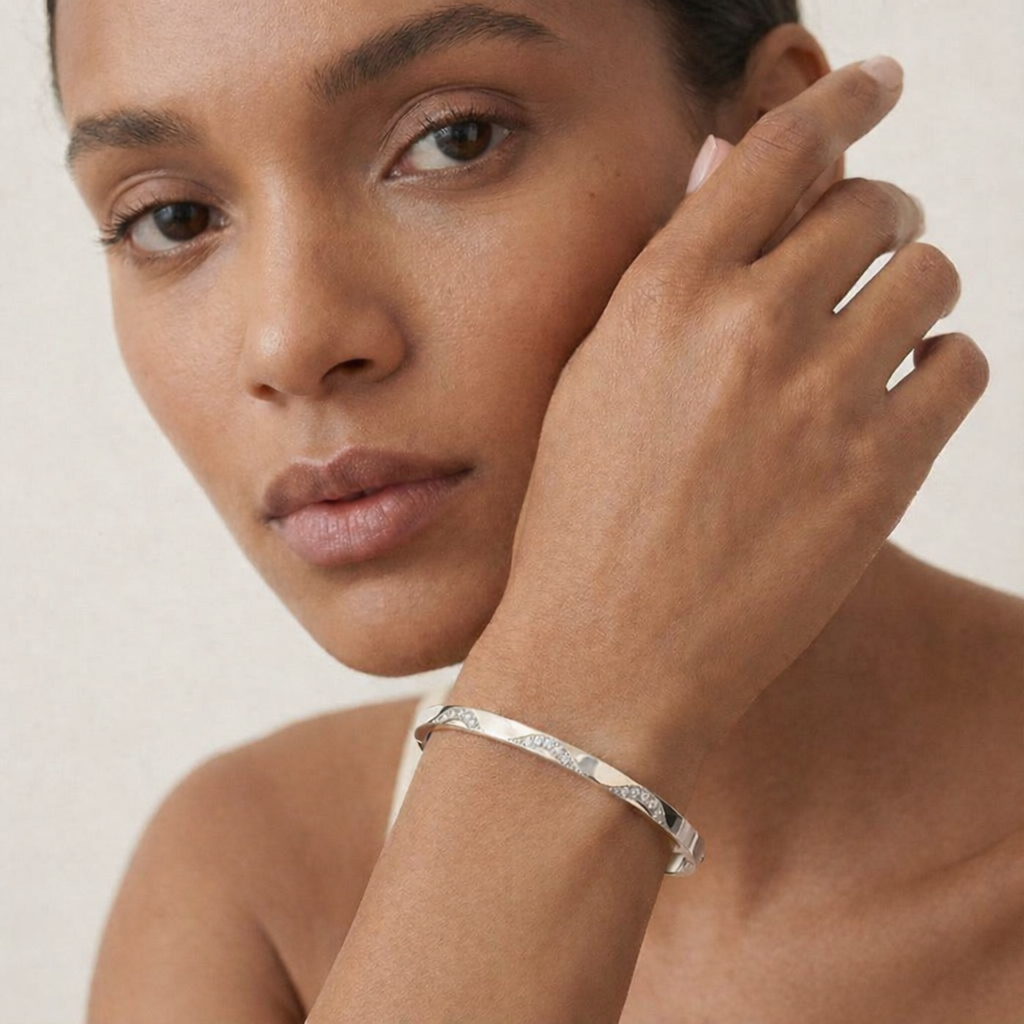 Woman wearing a silver bracelet on a plain background