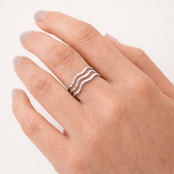 Silver ring on a finger against a white background