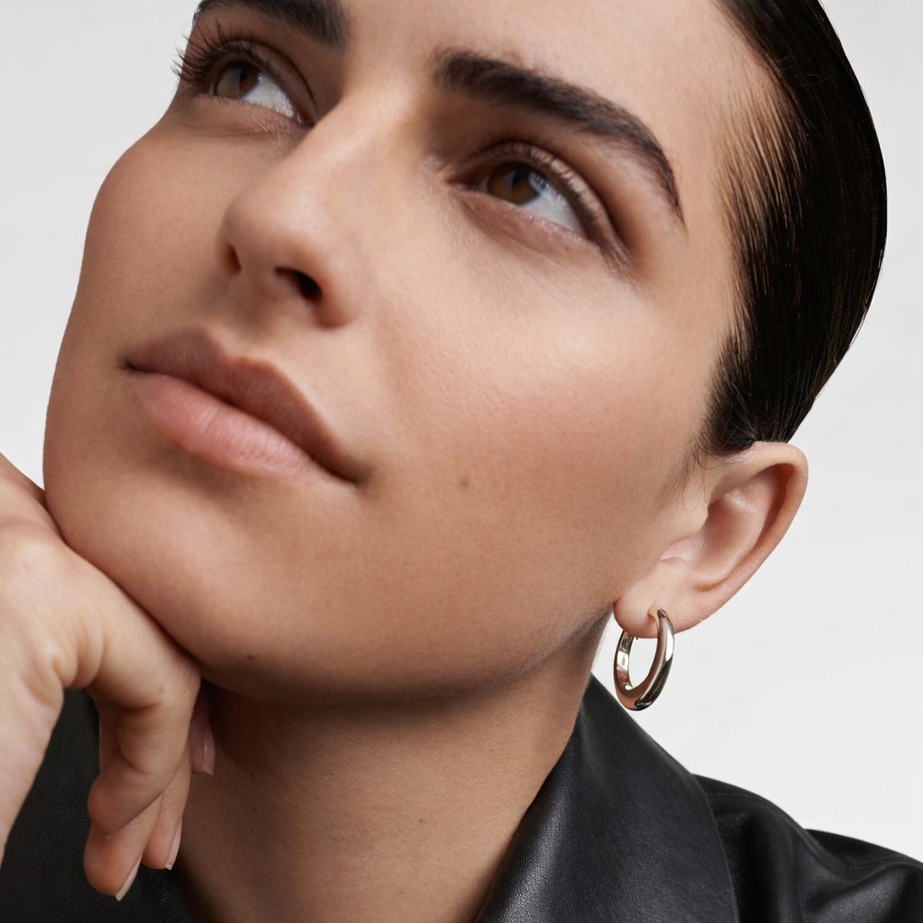 Close-up of a person wearing a hoop earring with a neutral background