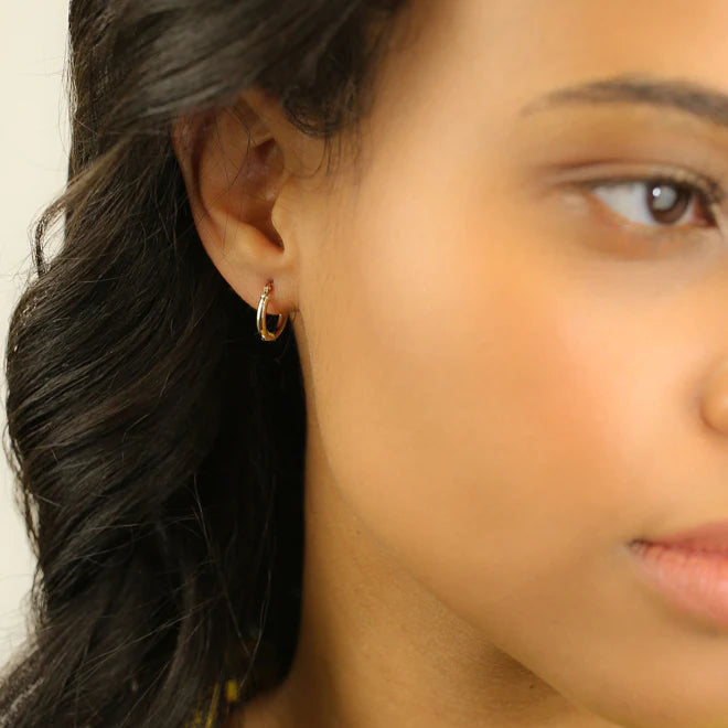 Close-up of a person wearing a gold hoop earring with a blurred background