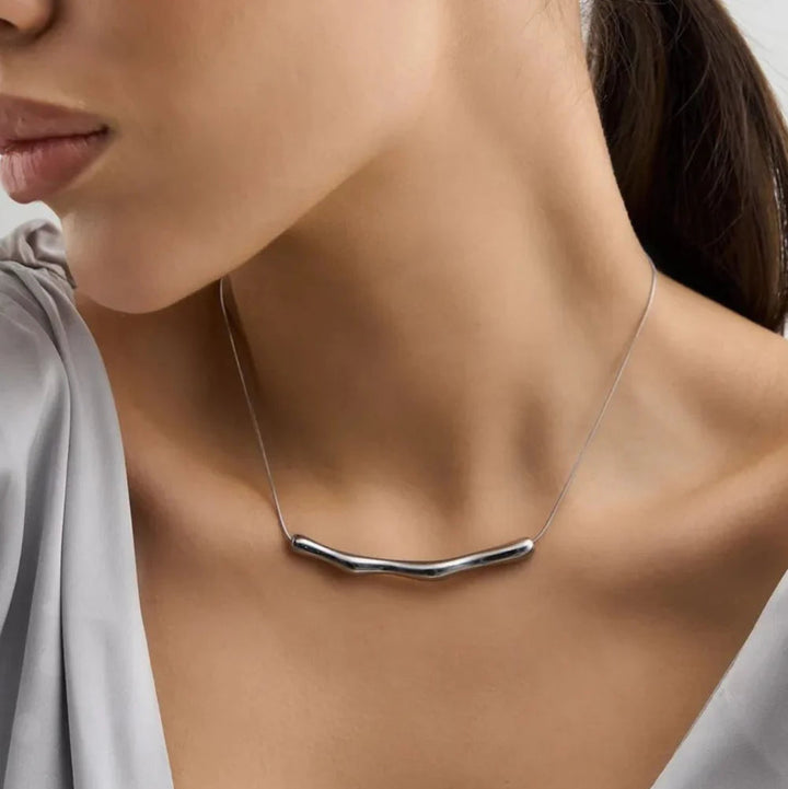 Silver necklace on a model wearing a light gray dress