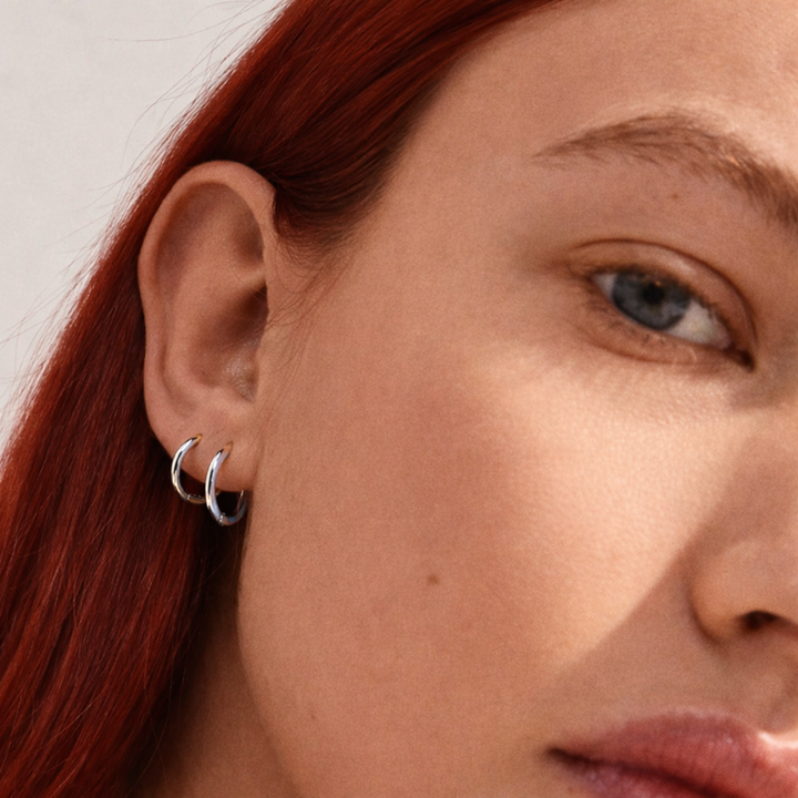 Close-up of a person wearing a gold hoop earring with a blurred background