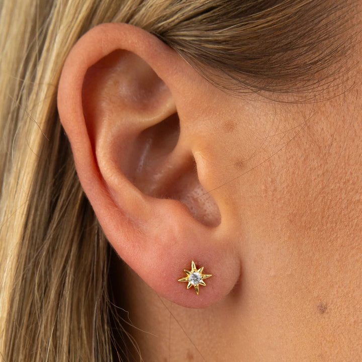 Close-up of an ear wearing a star-shaped earring with a gemstone.