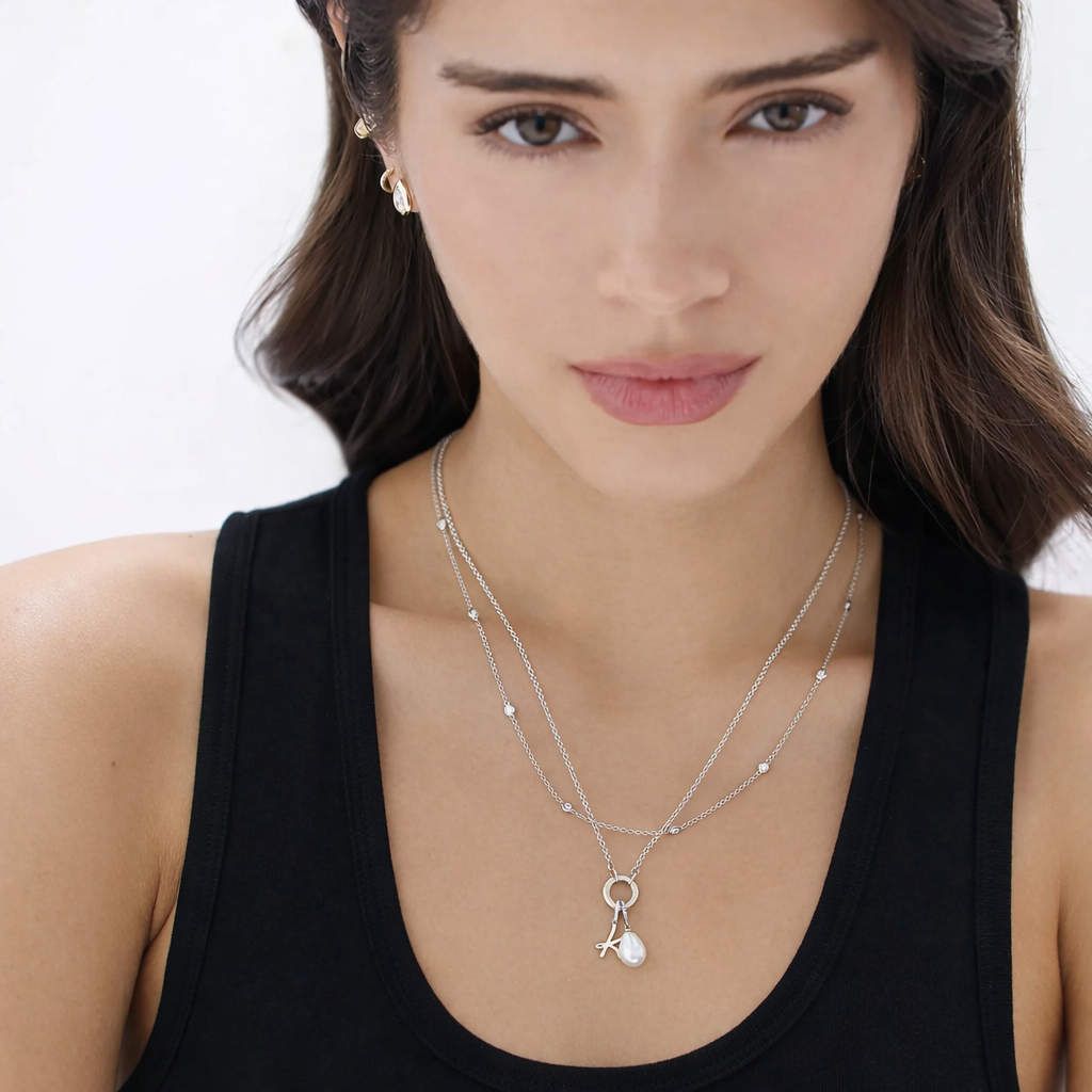 Woman wearing a silver necklace with a pendant against a white background